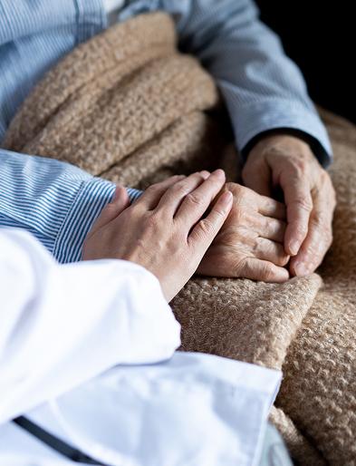 高齢者の手に優しく手を添える医療従事者